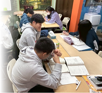 プレミアム個別指導の様子：講師1人に生徒3人が机で学習している場面