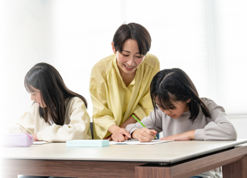 スタンダード個別指導の様子：講師1人に生徒2人が机で学習している場面